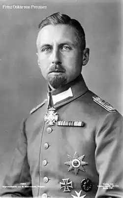 Oskar is pale-eyed, has a short goatee and wears uniform and medals