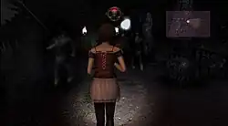 A horizontal rectangular video game screenshot that is a digital representation of a dark pathway lined with tall stones. A girl with her back to the viewer walks down the path towards translucent ghosts.