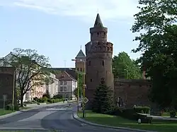 Medieval defensive walls and Baszta Sowia (Owl Tower) with the Saint Maurice and the Assumption of Mary church in background