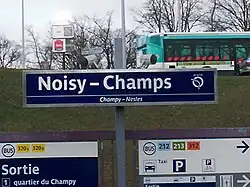 Sign indicating the name of the station (with a bus of line  213  in the background)