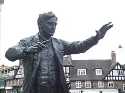 Outdoor statue of middle-aged man with raised arms as if conducting an orchestra