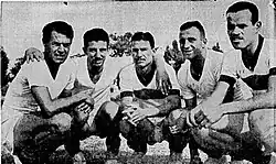 Black and while photo of a group of five Brazilian football player crouching together.