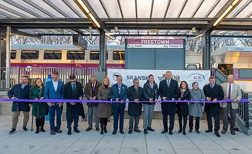 A group of people cutting a ribbon at a train station