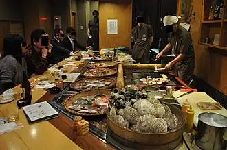 Activity at a robatayaki. Seafood and vegetables to cook displayed