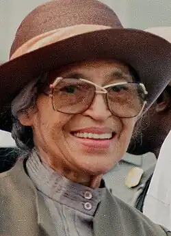 Rosa Parks as an older woman wearing a brown hat, giving a dignified smile.