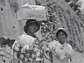 "Two Negro women carrying packages, one has a box of surplus relief commodities on her head. Natchez, Mississippi", 1940