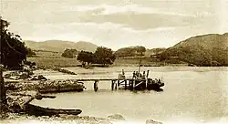 Passengers joining a small steamboat from a low pier
