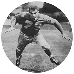 Alex Schibanoff in a Detroit Lions uniform and no helmet with his arms and legs spread out.