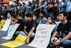 Seated protesters, holding placards