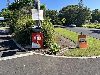 Lawn signs outside a polling station for the October 2023 constitutional referendum on establishing a Voice to Parliament for Australia's Aboriginal and Torres Strait Islander population. Lucas remarked on how the fourth episode - which centres on the debate about recognition of Australia's original inhabitants during the country's celebration of the 200th anniversary of the first British settlers landing, and the media treatment of protests and views that run against such a buoyant mood - happened to have aired during the campaign period.[56]