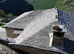 A slate roof in Syrrako (Greece), built with a curved valley layout and finials on top.