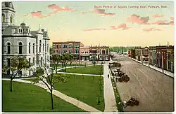 Old postcard, showing courthouse and commercial streets; several horse-drawn vehicles on street