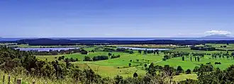 Rolling farmland with a thin lake in the middle ground and forestry in the distance