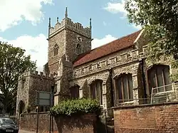 A stone church with a red tiled roof seen from the southeast showing the south aisle, south porch and tower