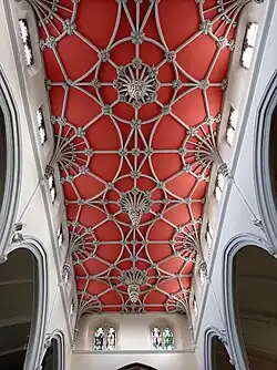 An ornate church ceiling with stone ribs on a red ground