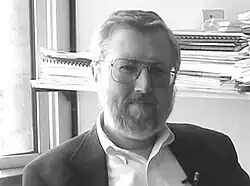 black-and-white image of Keith Stanovich wearing a shirt and tie, looking directly at camera with slight smile