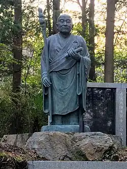 A statue of Ennin, an important disciple of Saicho with blue sky in the background, facing right