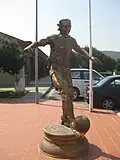 Statue of a footballer in sports facility gate.