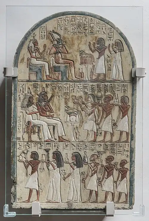 Funerary stela of Maya, limestone. Museo Egizio, Turin (C. 1579). The painted stela arrived in Turin with the Bernardino Drovetti collection in 1824. It was possibly discovered near the funerary chapel where Schiaparelli was to excavate roughly 80 years later. In the upper portion of the stele, Maya and his wife Tamyt pay homage to Osiris and Hathor, the gods of the necropolis. In the lower register is a similar, corresponding scene in which Maya and his wife receive food offerings, in their turn, from their many children, in keeping with a principle of reciprocity that is often found inn Egyptian religious thought.[4]