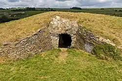 a grassy knoll, the top of which is surrounded by a stone retaining wall