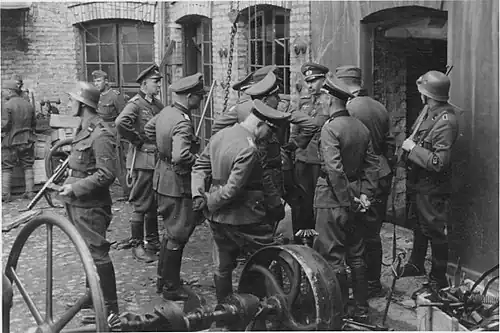 Stroop Report, showing Blösche at left. Original caption "Die Räumung eines Betriebes wird besprochen" {The clearance of a factory is being discussed-Herman Brauer helm repair shop at Nalewki 28–38. 24 April 1943}.