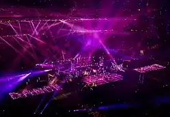 A faraway image of a stage with purple lights flashing from all around on it.