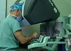 A surgeon sits with his face surrounded by a computer terminal.