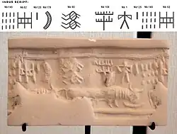 Impression of an Indus cylinder seal discovered in Susa, in strata dated to 2400–2100 BC. Elongated buffalo with line of standard Indus script signs. Tell of the Susa acropolis. Louvre Museum, reference Sb 2425.[61][63] Indus script numbering convention per Asko Parpola.[64][65]