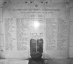 Une plaque en marbre blanc comporte sur quatre colonnes les noms des victimes de l'holocauste