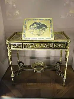 Writing table of Marie Antoinette; by Adam Weisweiler; 1784; oak, ebony and sycamore veneer, Japanese lacquer, steel, bronze gilt; 73.7 x 81. 2 cm; Louvre[71]