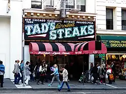 Sign reads "New York / Chicago Cincinnati / Detroit / Philadelphia / TAD'S Broiled STEAKS, surrounded by lights.