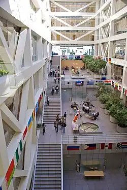 Large open building with granite steps running up the left side of the multi-storey building and modern fountains centered on each floor