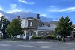 The photograph shows a one story building on the right (the Sub-Treasury) and a two story building on the left. Both are made of bluestone.
