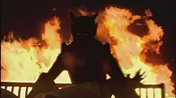 Silhouette of a demon, with fire in the background.