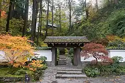 A garden with a Japanese gate featured in the center of the frame.