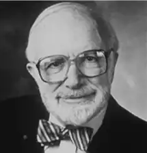 A black and white photo of an older man with glasses wearing a bow tie.