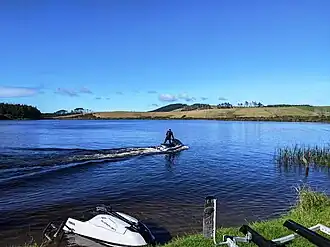 A jetskiier on a lake surrounded by farmland on a sunny day