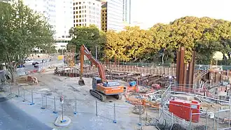 Construction site with an excavator sitting there. Excavation of the station box has begun.