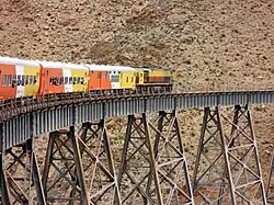 Orange, yellow and white train crossing a ravine