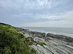 The rocky shoreline of Two Lights State Park with the open ocean beyond it.