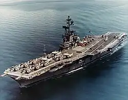 Medium-size aircraft carrier with numerous aircraft on its flight deck.