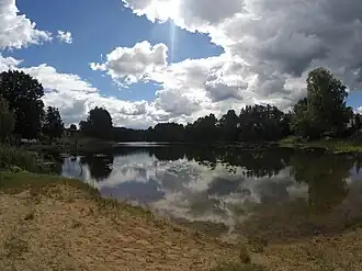 A photo of Kose Valgjärv showing the lake reflecting white clouds overhead