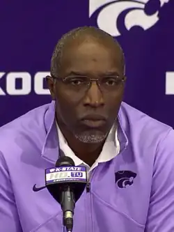 Van Malone from about the chest up in front of a microphone.