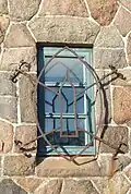 Iron detail on one of the windows adjacent to the entrance door depicting the tower itself.