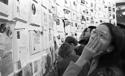 People looking at papers and pictures on a wall