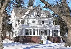 Two-story frame house with brick foundation, in snow
