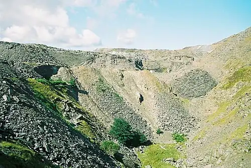 Heaps of waste slate lie on the sides of a deep quarried depression in the earth on Kirkby Moor.