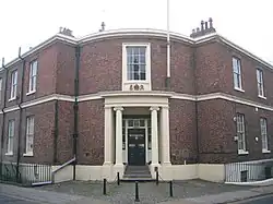 A Neogothic brick house with stone dressings and a curved porch on a street corner