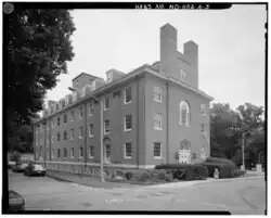 A photograph of a four-and-a-half-story brick building with a pitched room and two chimneys on its near end