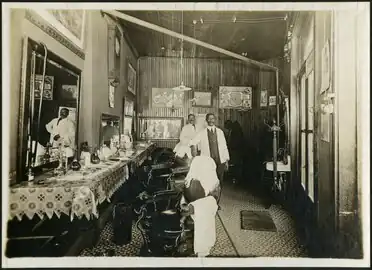A barber shop in Essex County, Ontario, c. 1900, with the photographer visible in the mirror at the back